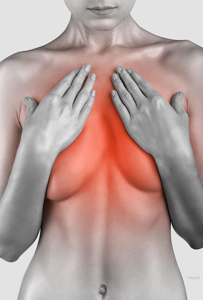 Woman with her hands over her breasts. Chest pain concept.