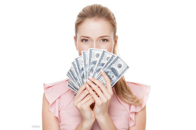 Woman fanning cash in front of her face.