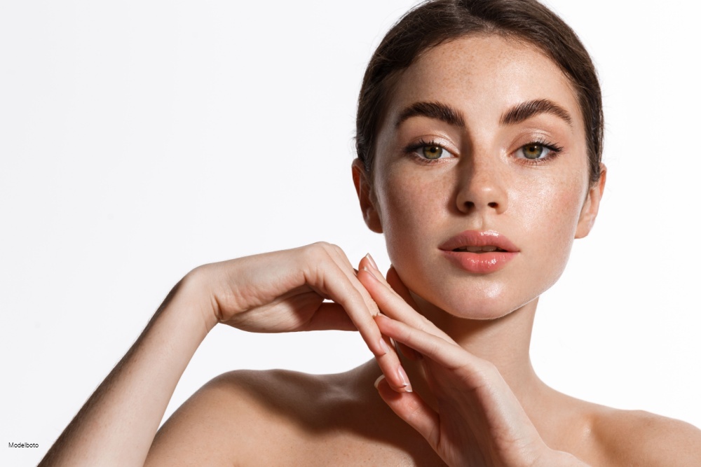 Woman with smooth and glowing skin looks at the camera.